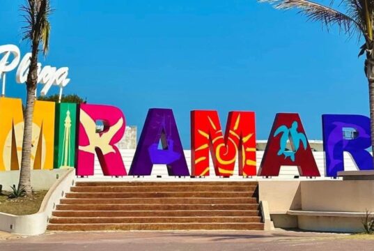 ¿Qué debes saber antes de viajar a la Playa Miramar? Letrero de la Playa Miramar con palmeras